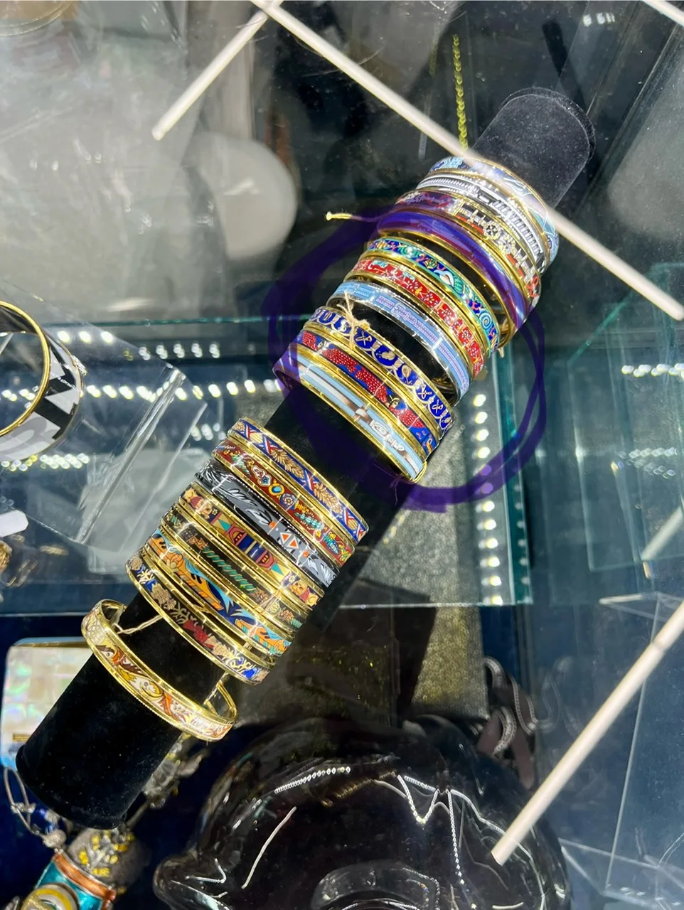 A colorful collection of enamel bracelets in a display case